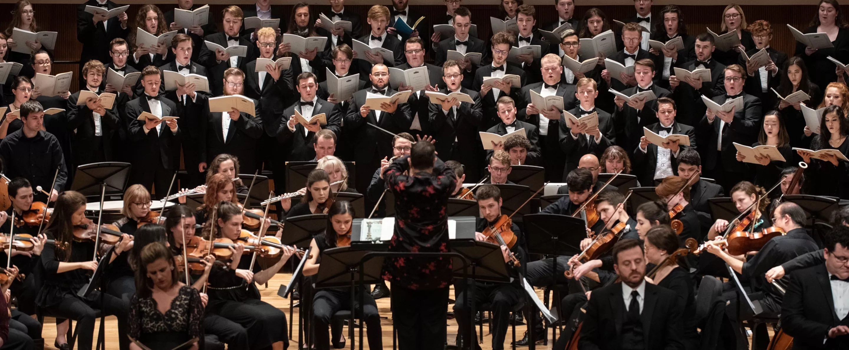 Students playing instruments and singing in a music symphony concert.