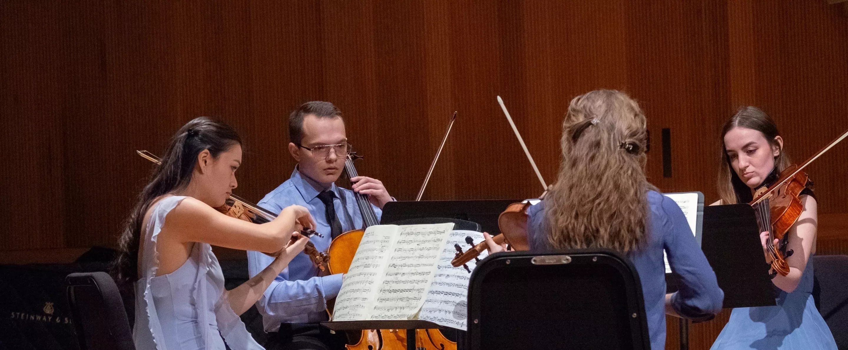 Four students playing string instruments