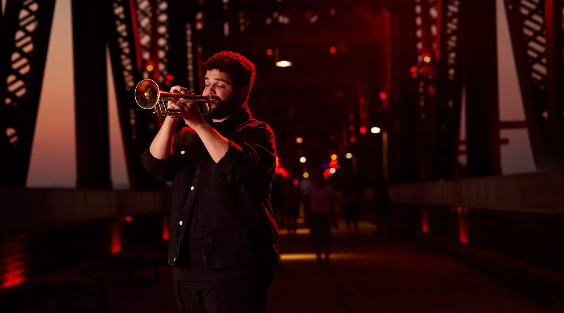 Connor May can be seen playing his trumpet on Big Four Bridge during the sunset.