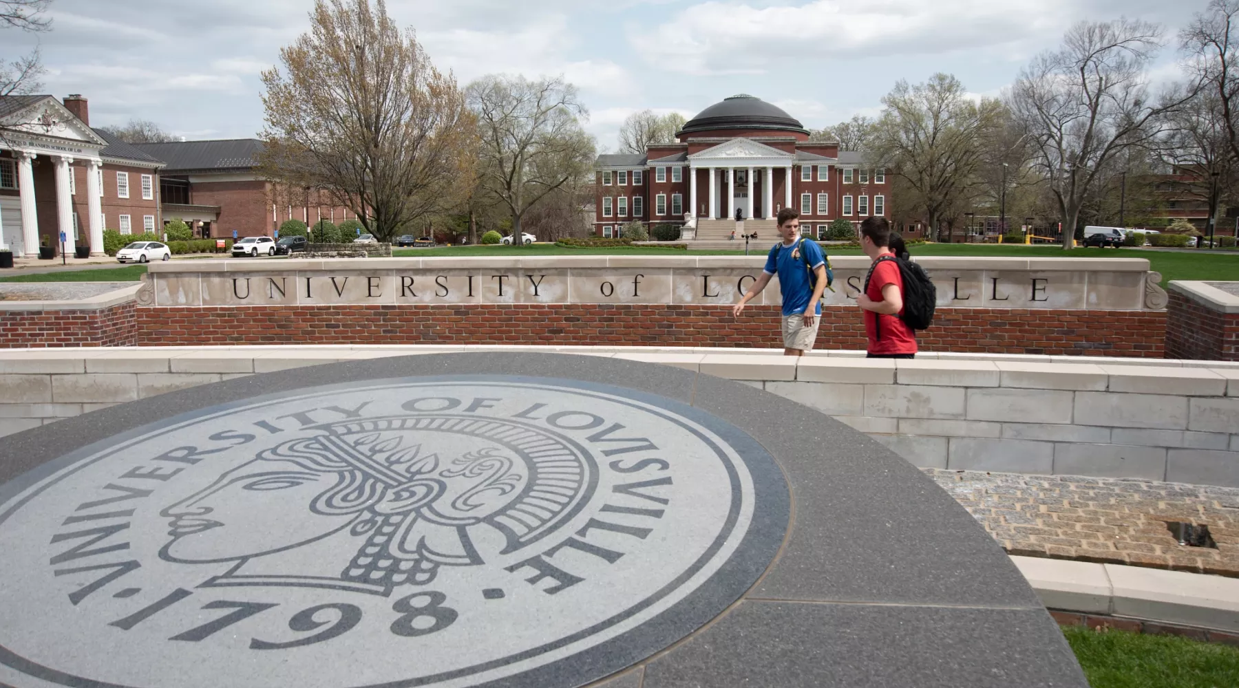 Three students walking past the 3rd Street entrance with Grawemeyer Hall and the School of Law in the background.