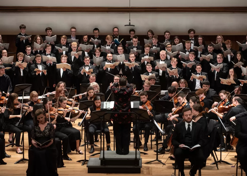 Students playing instruments and singing in a music symphony concert.
