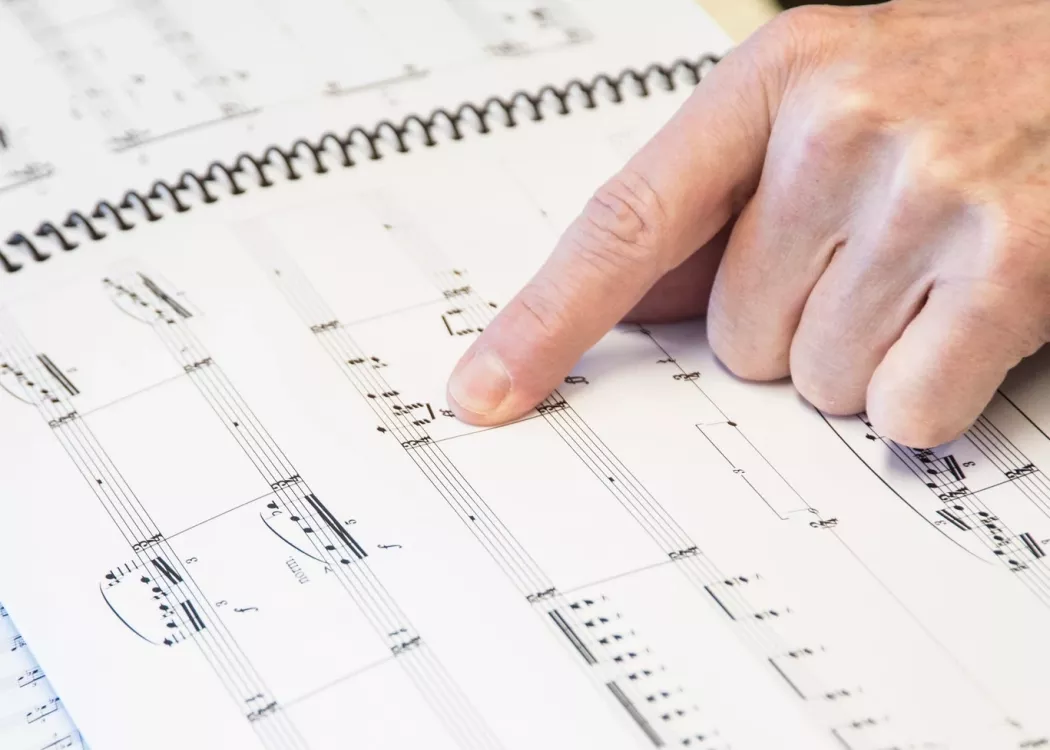 A hand pointing out music notes
