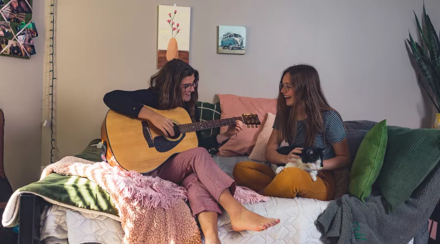 Music  therapy majors Caroline Rushing and Mackenzie Aldridge entertain each other in the Rose Anna Hughes Home room they share with cat Louie.