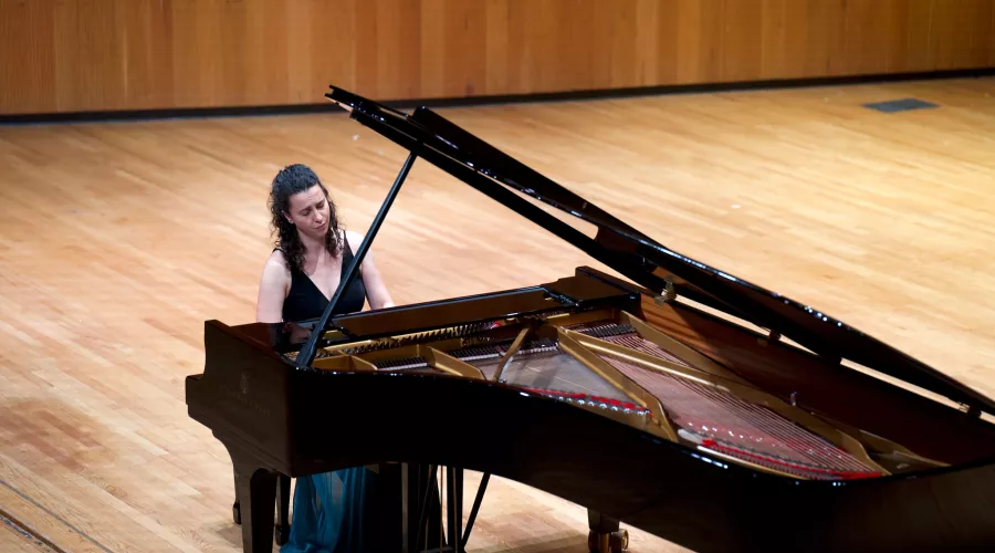 Faculty member playing piano on Comstock stage