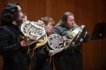 Four students playing french horn